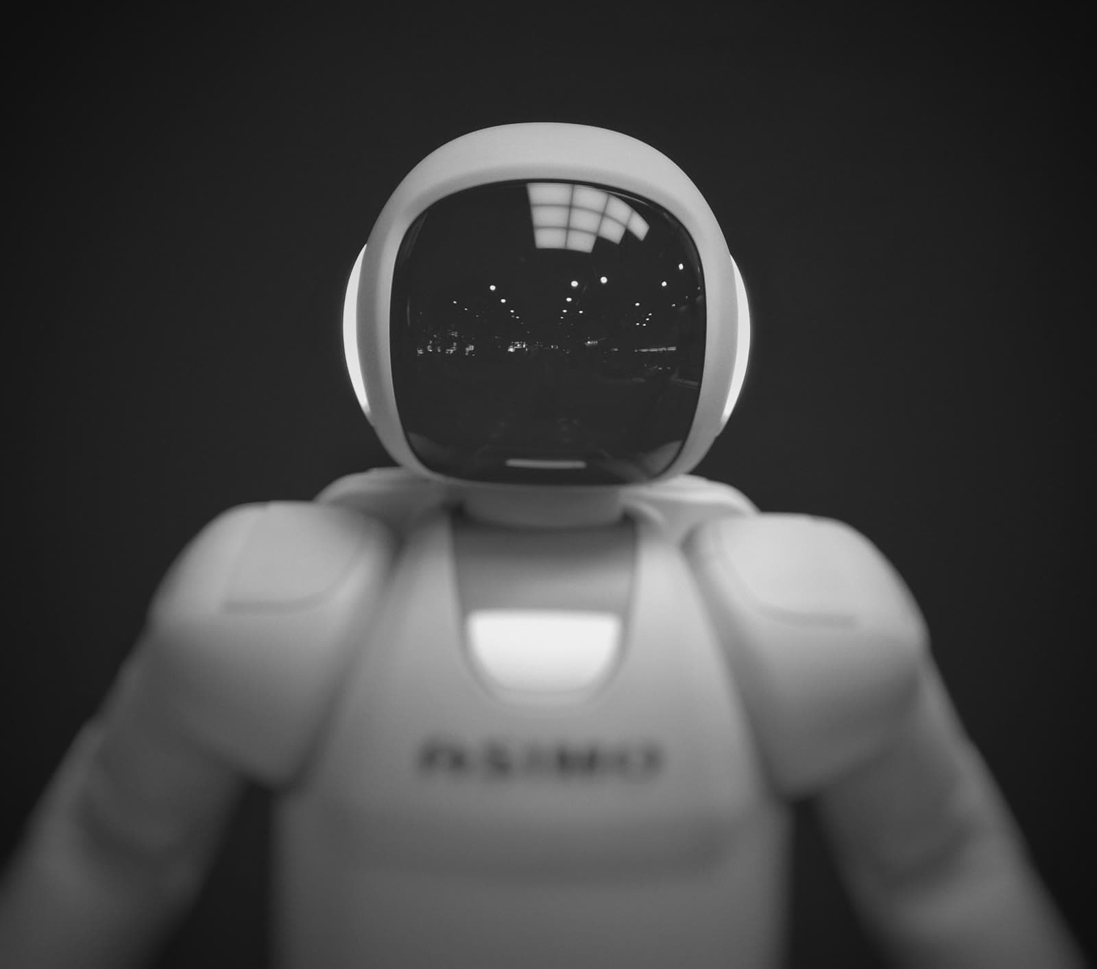 Karanlık zeminde duran beyaz insansı robot